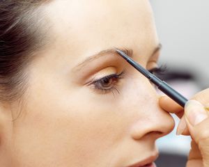 Woman getting her eyebrows filled in with a pencil