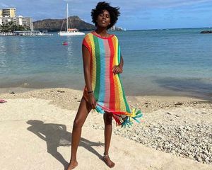 Model wearing a rainbow crochet dress on the beach.