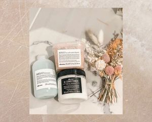 Davines hair products next to a dried bouquet on a stone and marble background