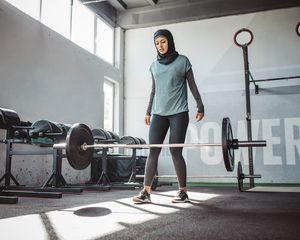 Woman in a gym, having just dropped weight bar with dumbbells