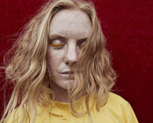 Woman with strawberry blonde hair, wearing a yellow shirt