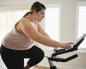 Woman adjusts the settings on her stationary bike.