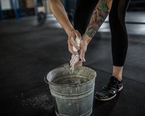 Woman applies chalk to her hands from a bucket