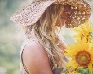 Blonde woman with a sun hat and sunflowers