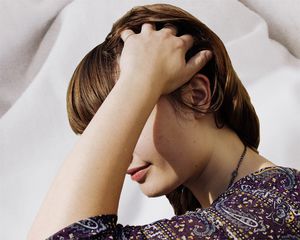 woman running hands through hair on cream background