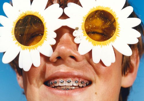 man with braces and flower sunglasses