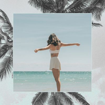 woman standing with her hands extended in front of water on a beach