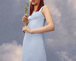 Model wearing seersucker blue dress holding a flower.