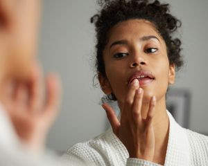woman checking lips in mirror
