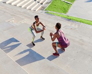 Two women perform squats outdoors.