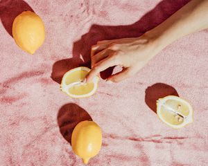 woman holding lemon against pink background
