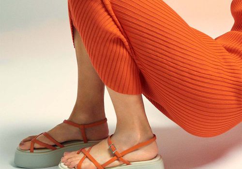 Model wearing an orange knit dress and Vagabond Shoemakers sandals.
