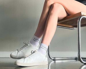 Woman wearing Thousand Fell sneakers sitting on a cane chair