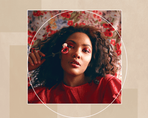 Black Woman with Natural Hair Against Floral Background Holding a Flower with Bright Pink Eyeshadow