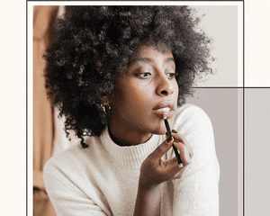 BIPOC Woman Looking at Reflection and Applying Berry Colored Lip Liner Around Her Lips