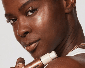 Jones Road Shimmer Face Oil Model holding bottle