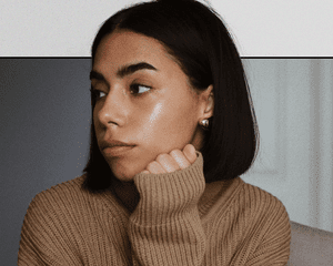 Portrait of Woman Looking Off to the Side with Dewy Skin and Highlighter on Her Cheek